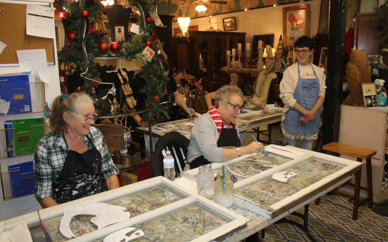 Tina Teasley (from left) and Tami Saperstein paint a snowman on window panes during an art class at the Blue Goose Studio on Thursday afternoon during the Downtown Art Stroll. (TONY BRITT/Lake City Reporter)