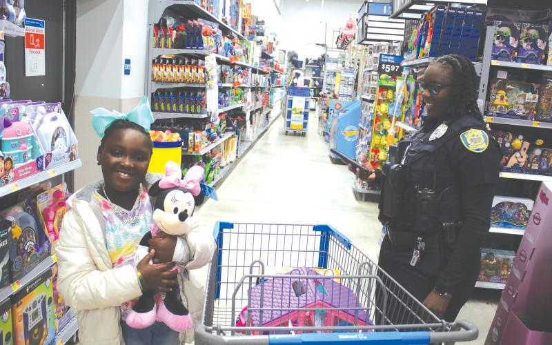 Callie Jones, 7, hugs her Minnie Mouse plush toy while shopping with Lake City Police Officer Aumaria Kelly during Wednesday morning’s Shop With A Cop event. (TONY BRITT/Lake City Reporter)
