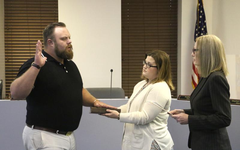 James Carter (left) is sworn in as a member of the Lake City Council by City Clerk Audrey Sikes (right) on Monday night after being appointed to the District 13 seat. Carter’s wife, Jenna, holds the Bible for the ceremony. (MORGAN MCMULLEN/Lake City Reporter)