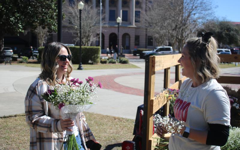 Erin Crumitie (from left) purchases a bouquet of flowers from Alyssa Roxby on Wednesday morning in Olustee Park during a Valentine's Day pop-up event for local vendors. (TONY BRITT/Lake City Reporter)