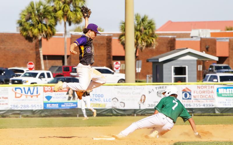 Columbia shortstop Grant Bowers jumps high for a throw as Venice runner Maddox Volk slides safely into second base on Tuesday. (BRENT KUYKENDALL/Lake City Reporter)