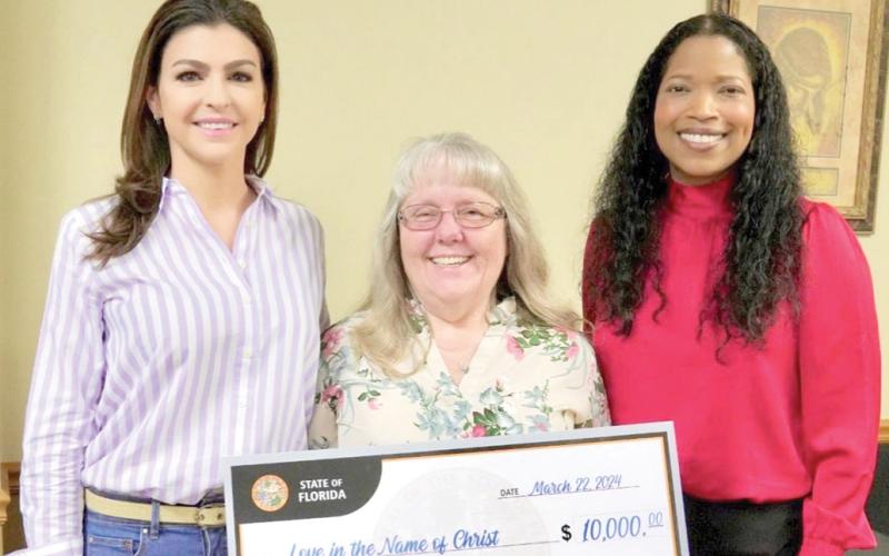 Love INC of Suwannee County Executive Director Martha Wood (center) receives a $10,000 award from First Lady Casey DeSantis and Department of Children and Families Secretary Shevaun Harris on Friday in Live Oak. (COURTESY)