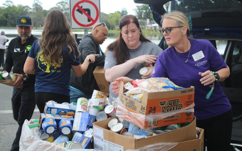 Shannon Moser (from left), Catholic Charities Lake City Regional Director, and Renee LeBlanc fill a box with canned goods and other food items donated by Circle of Life Assisted living facilities. Catholic Charities held its March Against Hunger Walk on Tuesday afternoon at Lake DeSoto. (TONY BRITT/Lake City Reporter)