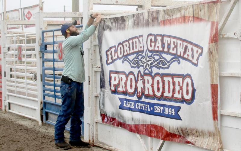 Dyllan Romanik attaches a sign in the Florida Gateway Fairgrounds rodeo arena ahead of the 30th annual Florida Gateway Pro Rodeo, which will take place Friday through Sunday. (TONY BRITT/Lake City Reporter)