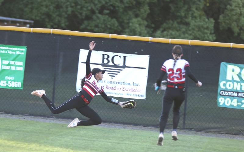 Fort White center fielder Morgan Kelly stretches out for a diving catch against Baker County as right fielder Taryn Clyatt looks on Thursday. (MORGAN MCMULLEN/Lake City Reporter)
