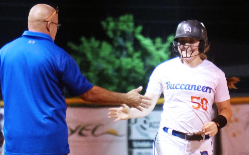 Branford's Ellie Frierson high fives head coach Oscar Saavedra as she rounds third base after hitting a home run against Suwannee on Tuesday. (PAUL BUCHANAN/Special to the Reporter)