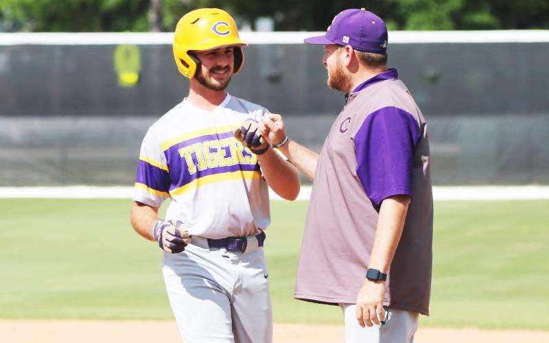 Columbia first baseman Philip Maddox fist bumps assistant coach Joey Edge after hitting an RBI single during Tuesday’s win over The Villages Charter. (JORDAN KROEGER/Lake City Reporter)