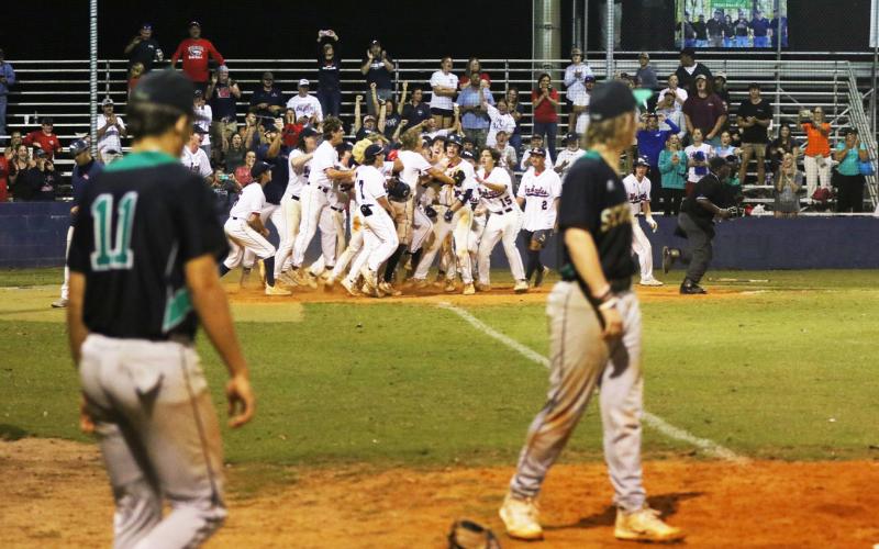 Suwannee’s Logan Brooks and Grayson Greene look on at Wakulla’s celebration at home plate following Hayden Klees’s walk-off home run in the Region 1-4A quarterfinals on Wednesday. (MORGAN MCMULLEN/Lake City Reporter)